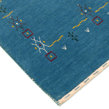 Corner and edge detail of teal blue Loom Lori wool rug showing geometric tribal motifs and traditional handcrafted finishing
