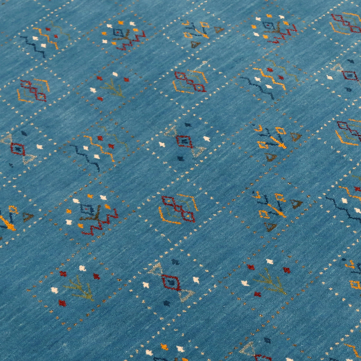 Close-up of teal blue Hand Woven Loom Lori wool rug showing dotted panels, geometric symbols and natural handcrafted wool texture