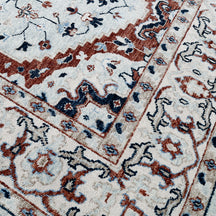 Detail view of hand knotted traditional wool rug in ivory navy and rust tones