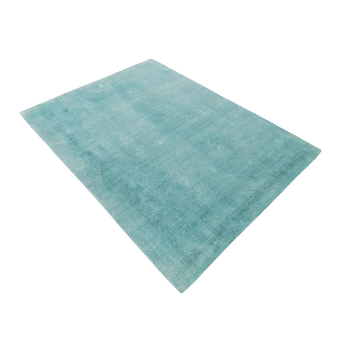 Side angle view of a turquoise rectangular hand woven Loom Lori wool rug showing its plain surface and soft tonal texture.