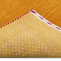 Corner and edge detail of mustard yellow Hand Woven Loom Lori wool rug showing dotted geometric border and handcrafted finishing